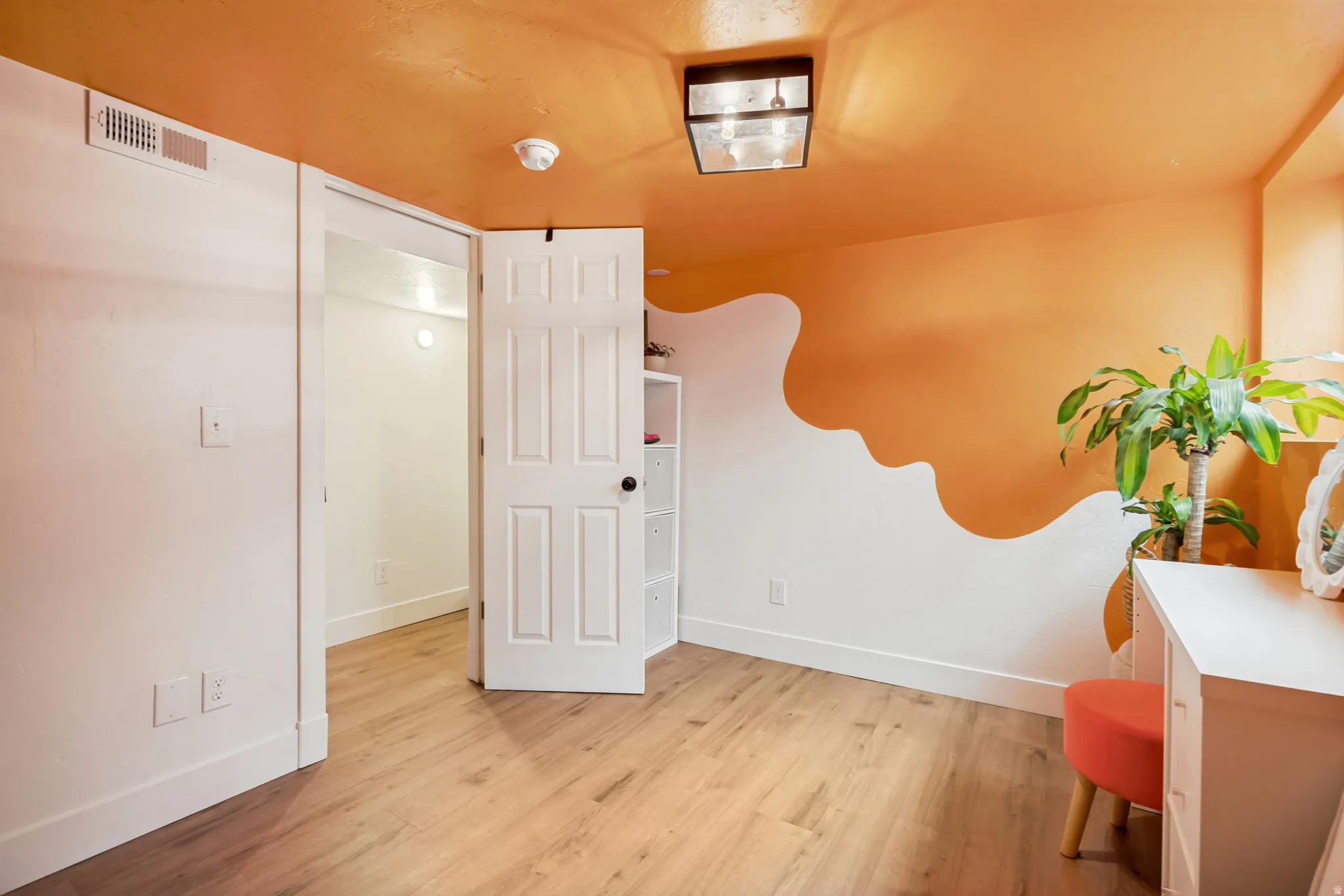 Room with wood-finish flooring, a contemporary ceiling light fixture, and a white interior door