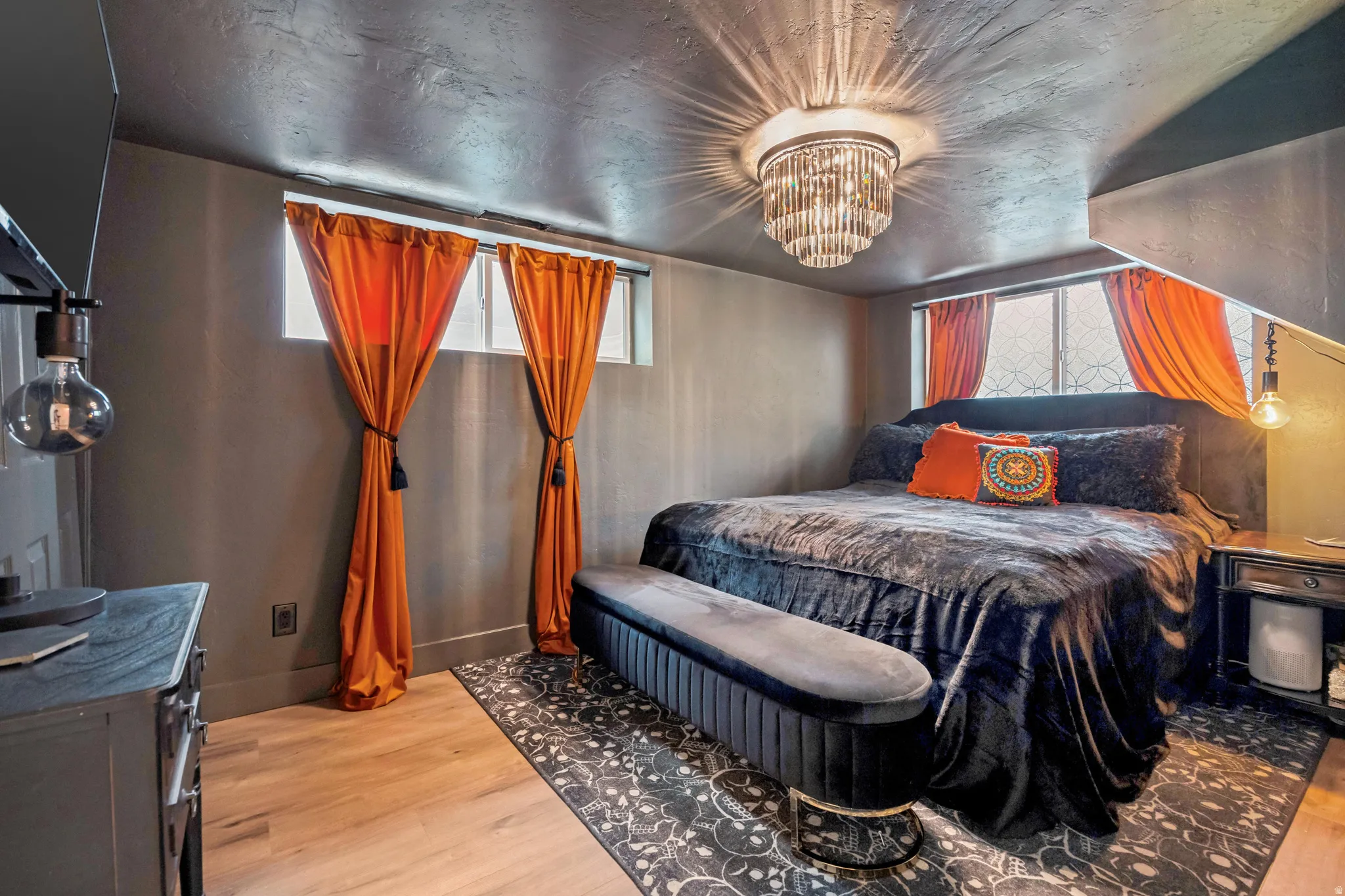 Bedroom featuring a contemporary chandelier, wood-finish flooring, and a window with custom decorative grilles