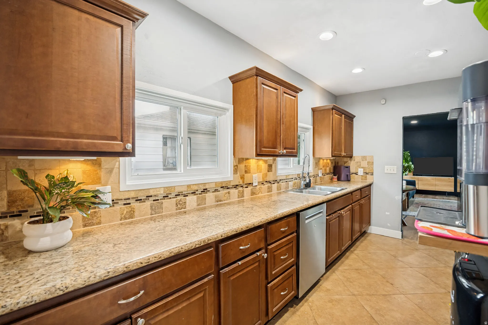 Kitchen featuring wood cabinetry, light-toned countertops, a mosaic tile backsplash, recessed lighting, and stainless steel sink