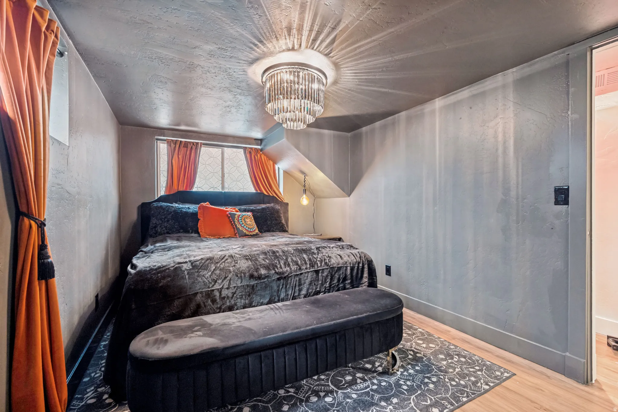 Bedroom featuring a chandelier light fixture, wood-finish flooring, and a window with orange drapes