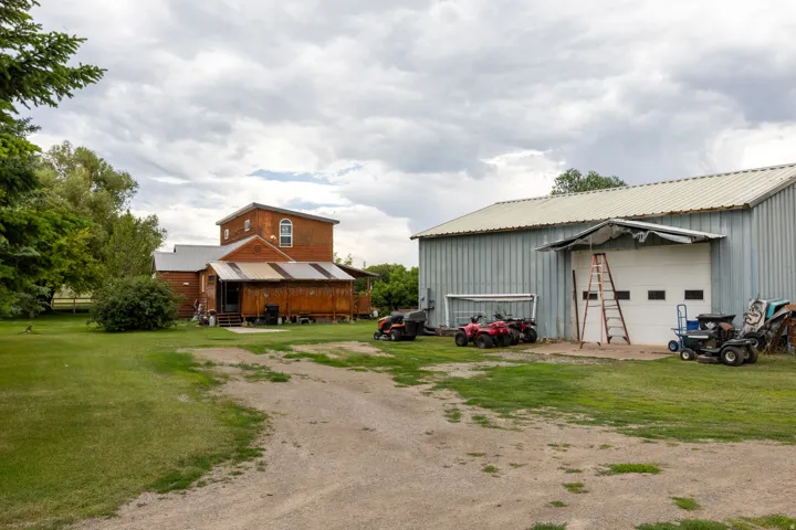 Spacious grounds featuring a detached metal-sided barn with a large garage door, a gravel driveway, and expansive lawn areas