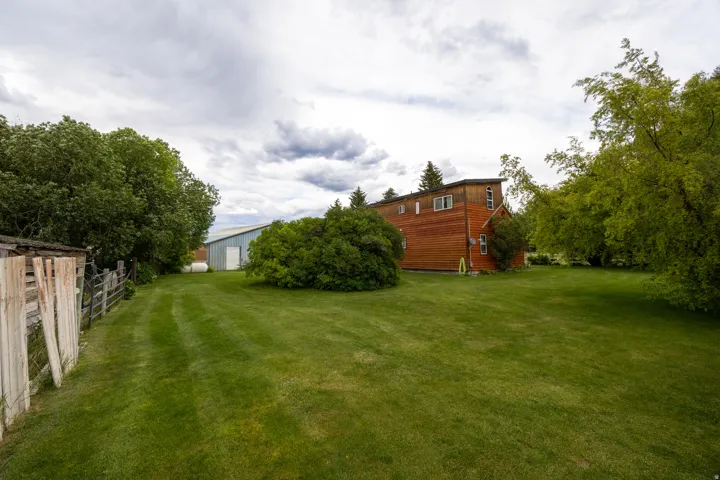 Expansive green lawn with mature trees bordering the property