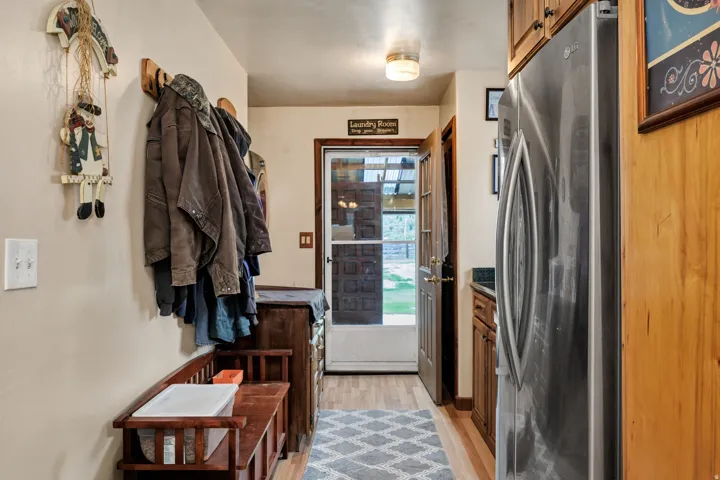 Entryway featuring wood-finish flooring, a stainless steel refrigerator, and wood cabinetry