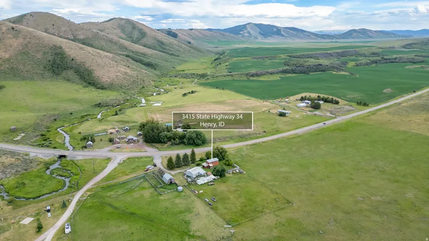 Aerial perspective showcasing a rural property with surrounding green fields and mountainous terrain