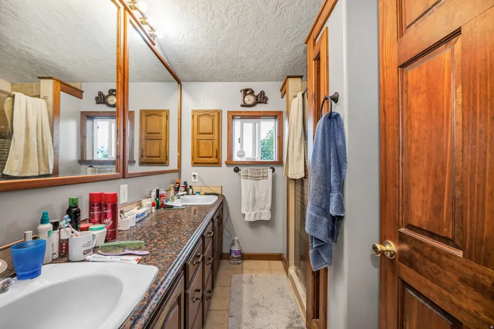 Double vanity featuring undermount sinks, a dark granite-style countertop, and rich wood cabinetry