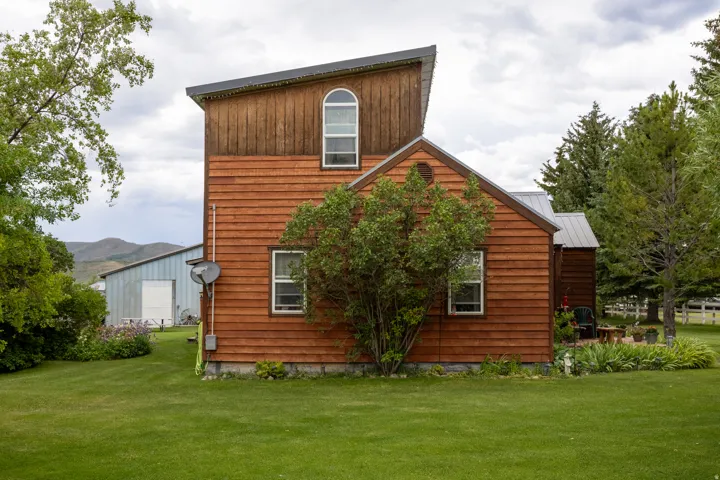 Wood-sided structure featuring a distinctive sloped roofline and an arched window
