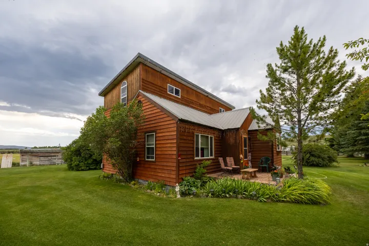 Wood-sided residence featuring a metal roof and a brick patio