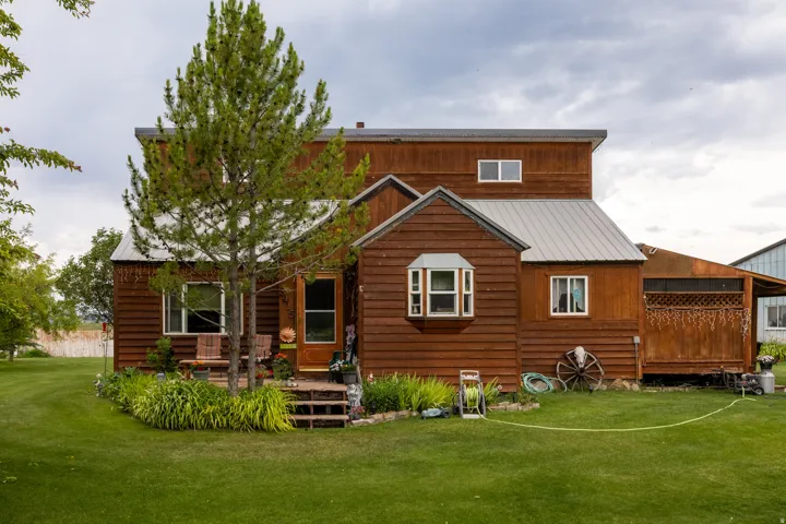 Rustic wood-sided exterior featuring a small front porch, bay window, and metal roofing elements