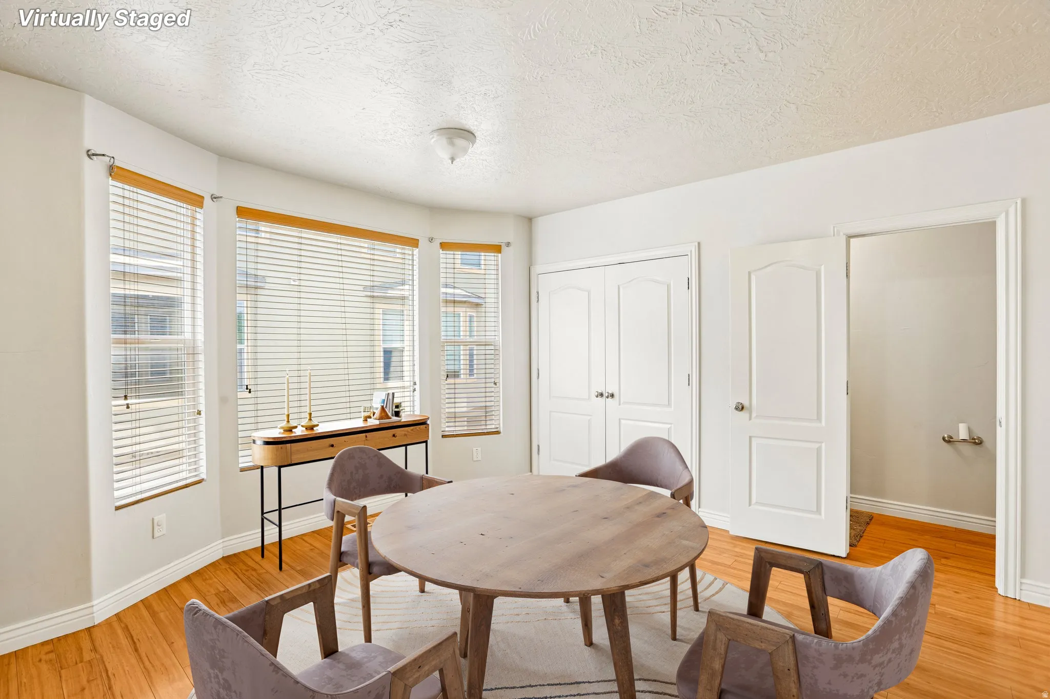 Recessed bay windows with wood-finish blinds, wood-finish flooring, white baseboards, and a ceiling-mounted light fixture