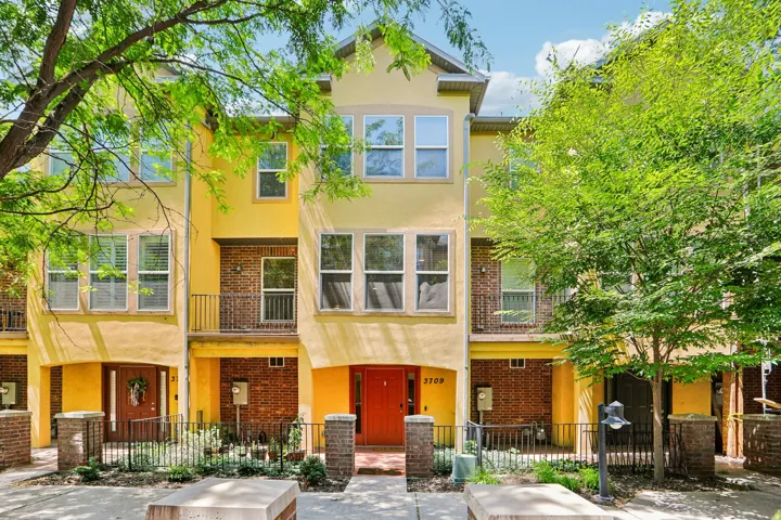 Multi-level townhome exterior featuring a stucco finish with brick accents and multiple balconies