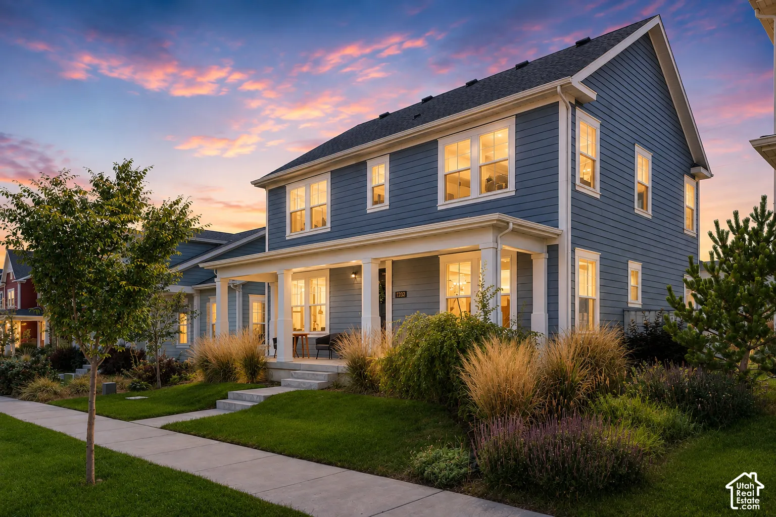 Two-story residence with blue siding, white trim, a covered front porch, and mature landscaping