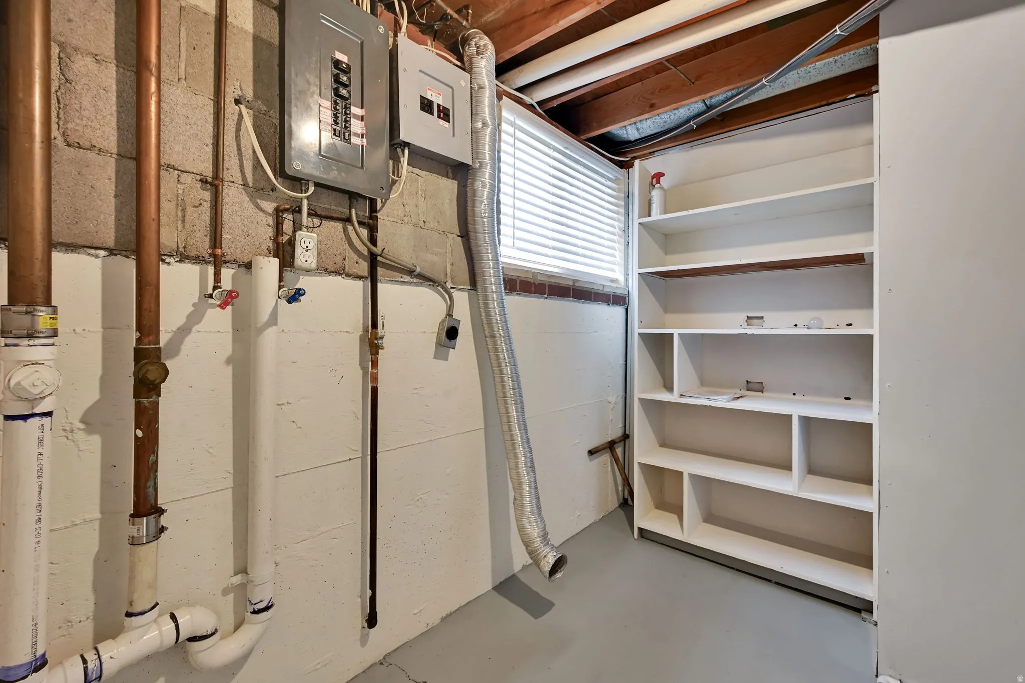 Utility area featuring exposed copper and PVC plumbing, an electrical panel, and built-in shelving