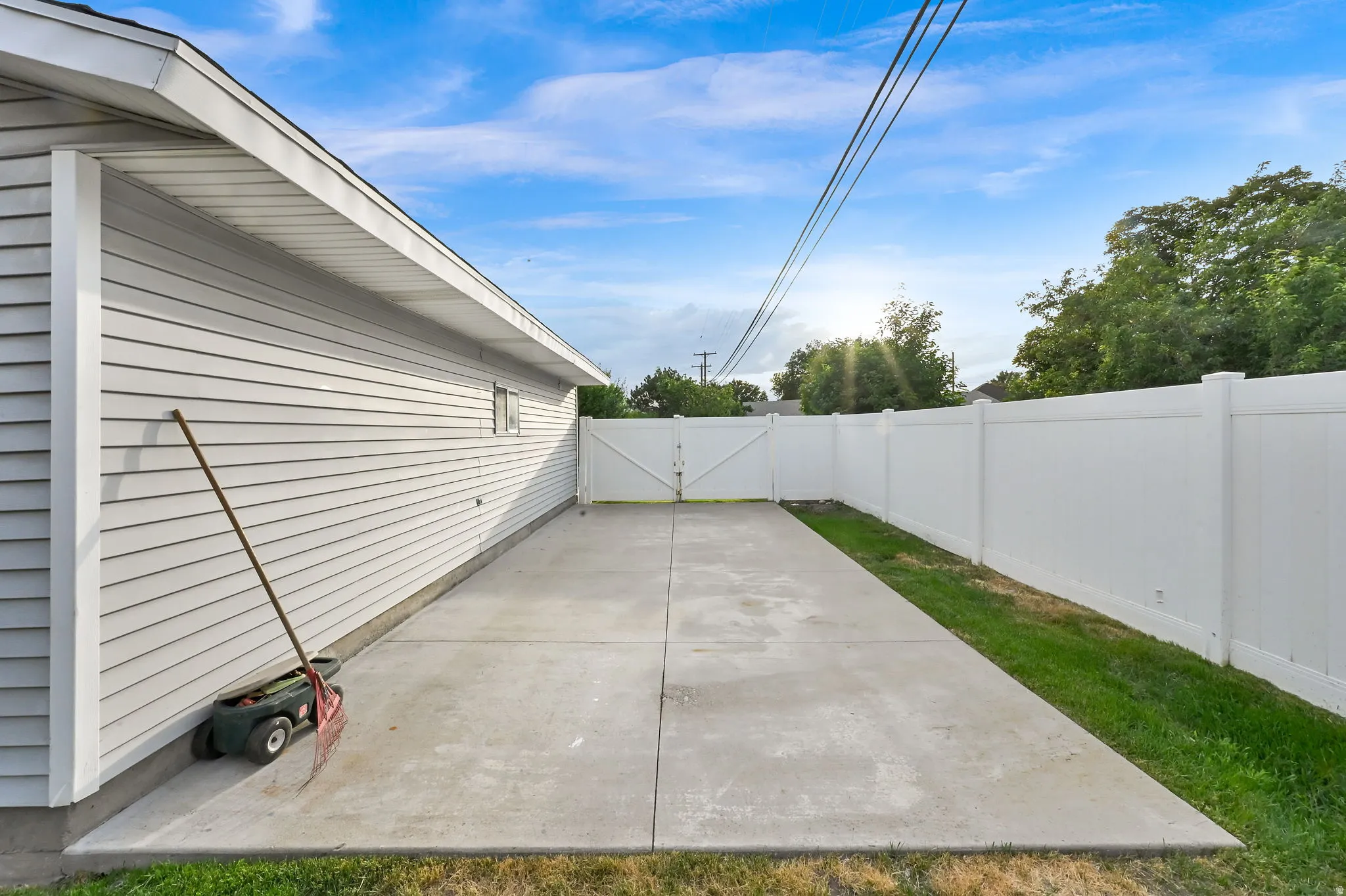 Concrete patio area with a white vinyl privacy fence and a white vinyl-sided exterior