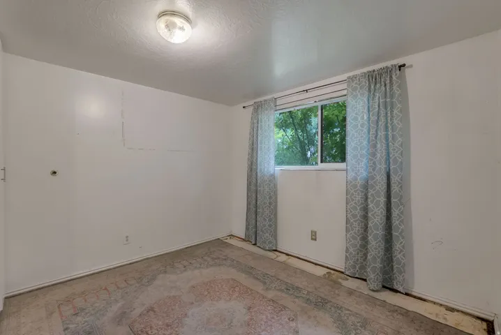 Room with a window featuring light-colored curtains and a flush-mount ceiling light