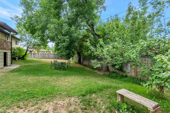 Expansive green lawn with mature trees and a private wood fence