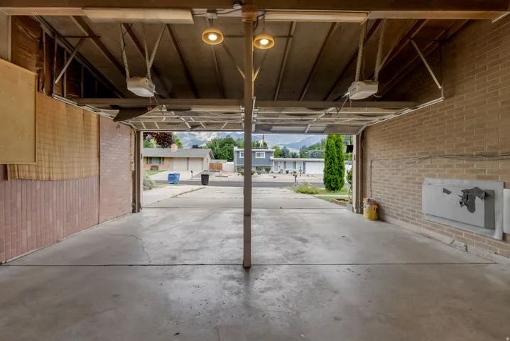 Two-car garage featuring brick walls, concrete flooring, and ceiling-mounted lighting