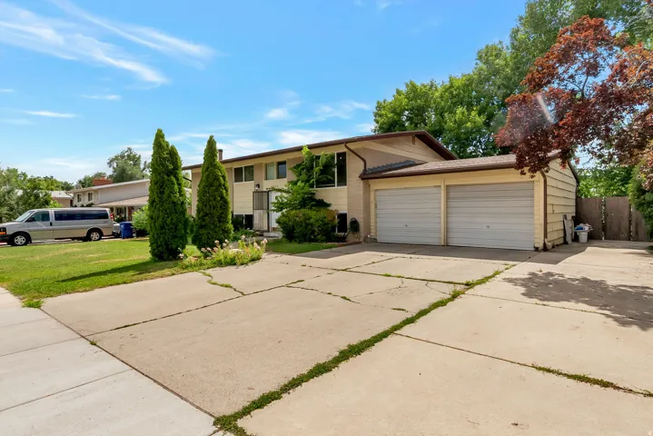 Two-story property with a two-car garage, mature landscaping, and a concrete driveway
