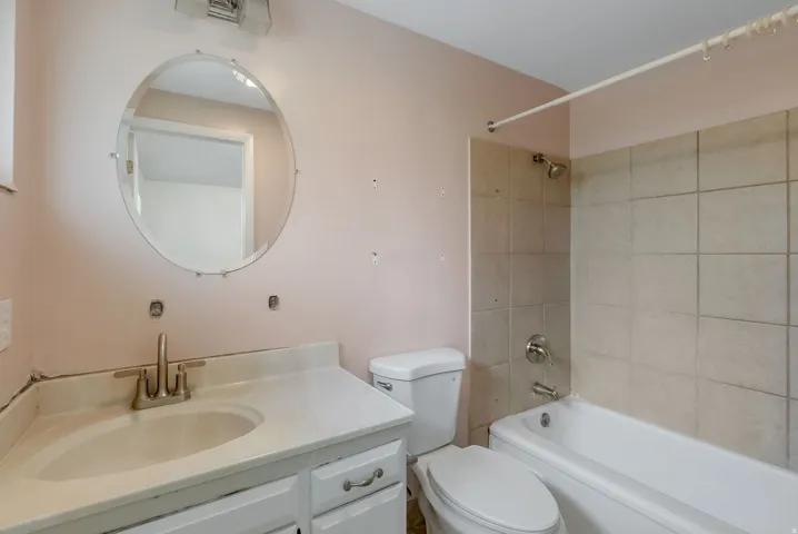 Bathroom vanity with an integrated sink, brushed nickel faucet, and a wall-mounted oval mirror