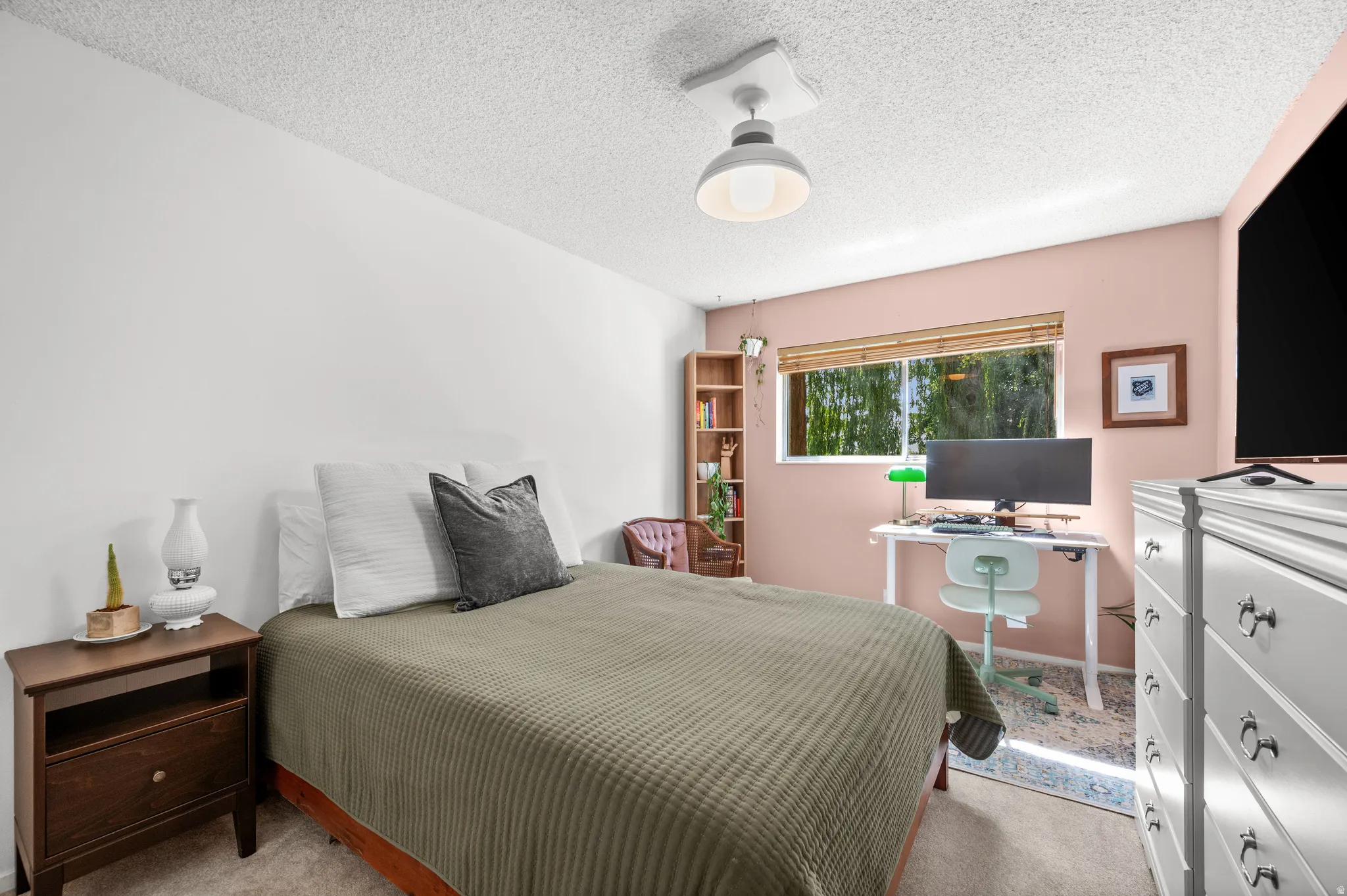 Bedroom featuring a window with bamboo blinds, a built-in wooden bookshelf, and a ceiling-mounted light fixture
