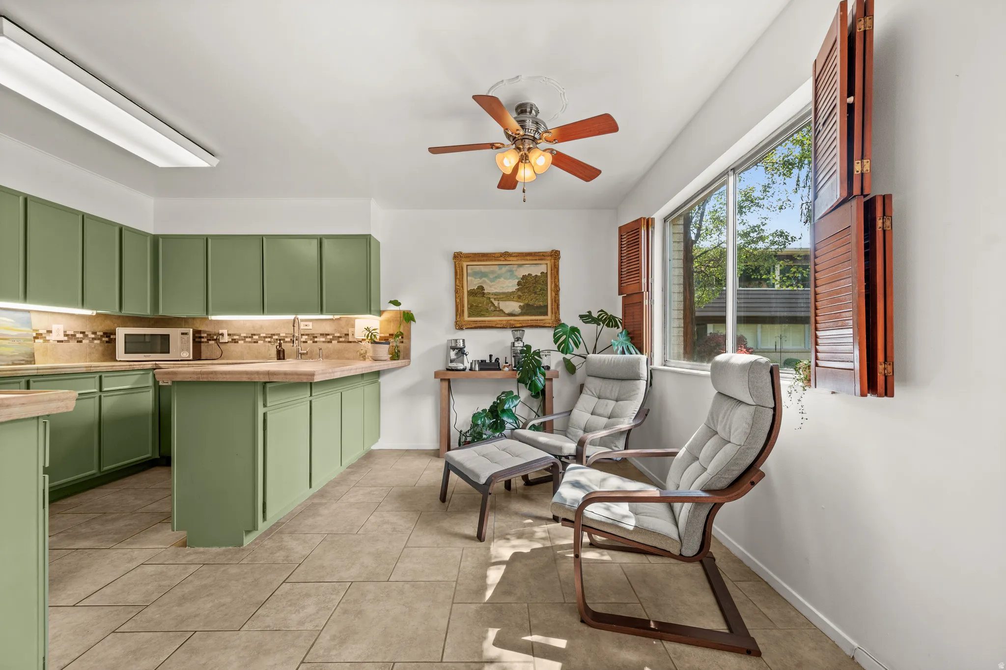 Kitchen area featuring sage green cabinetry, a multi-tone backsplash, and light-toned countertops