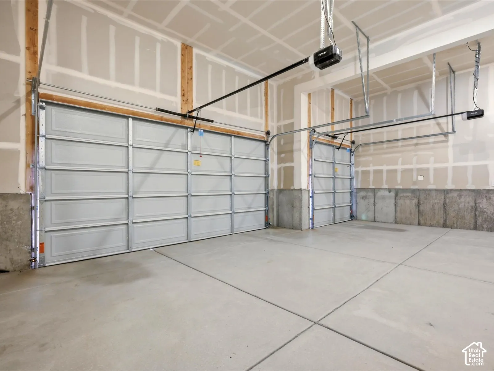 Attached garage featuring two overhead doors, concrete flooring, concrete foundation walls, and ceiling-mounted automatic door openers