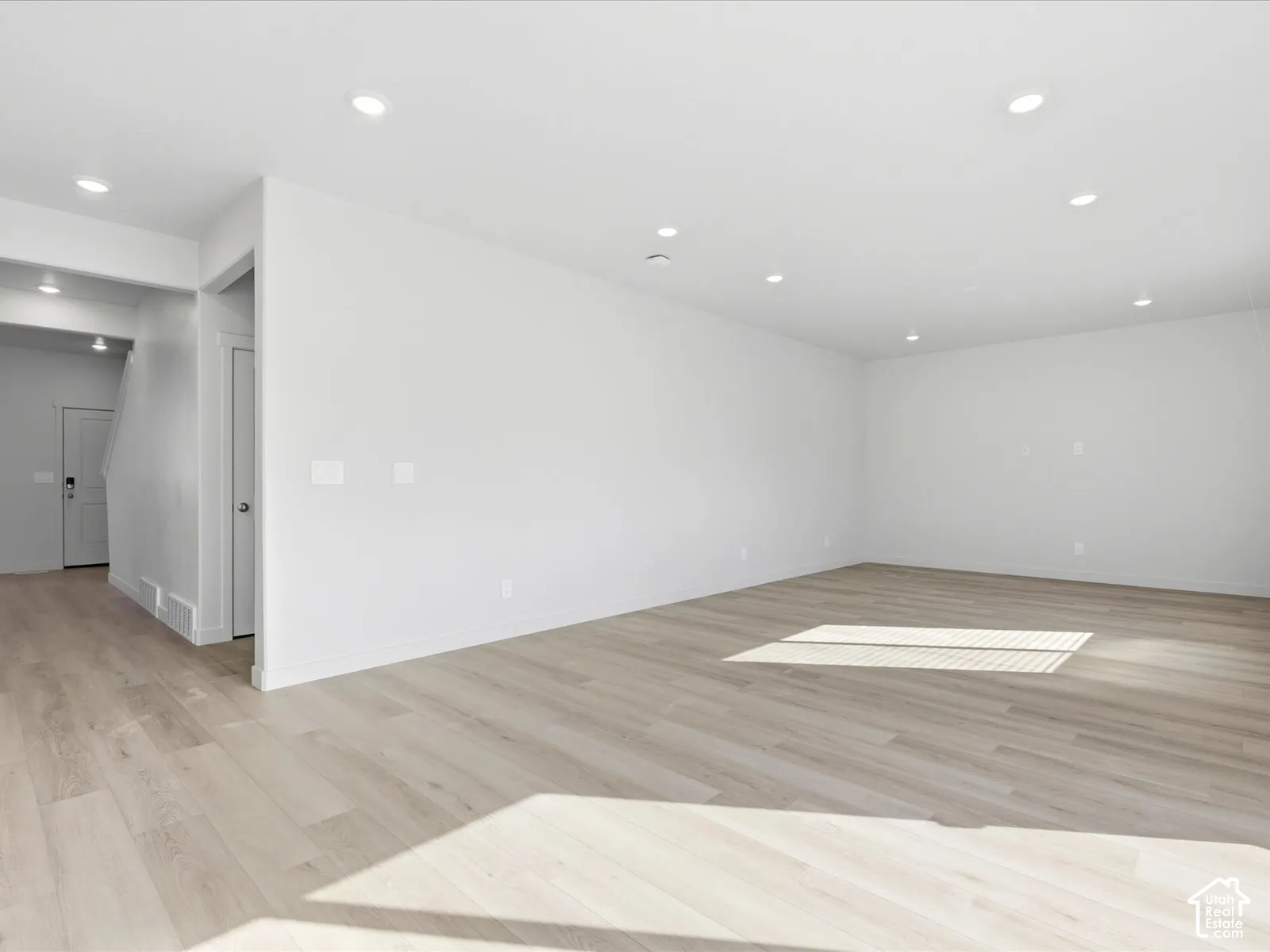 Neutral interior featuring wood-finish flooring, recessed lighting, and crisp white wall finishes