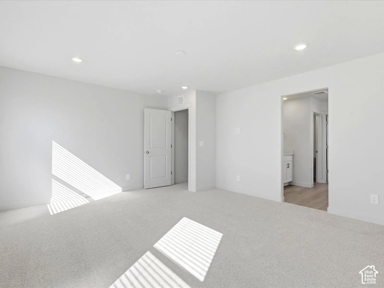 Neutral interior featuring wall-to-wall carpeting, recessed lighting, and a solid-core panel door