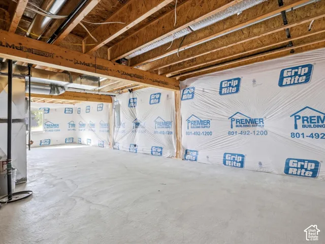 Unfinished basement space featuring exposed wood-joist ceiling, concrete flooring, and vapor-barrier wall wrapping