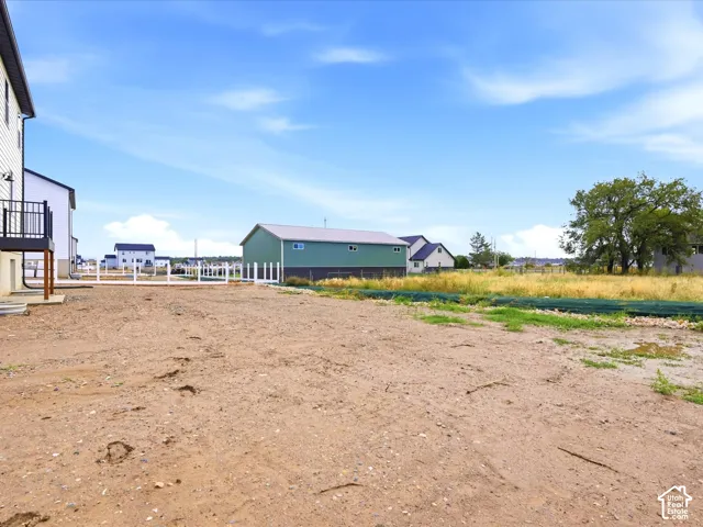 Expansive lot featuring a white vinyl perimeter fence, elevated deck, and detached metal-sided outbuilding