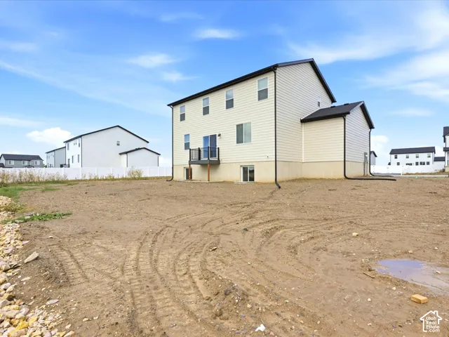 Two-story vinyl-sided exterior with a neutral color palette, dark roofing, rear elevated deck, and a white privacy fence