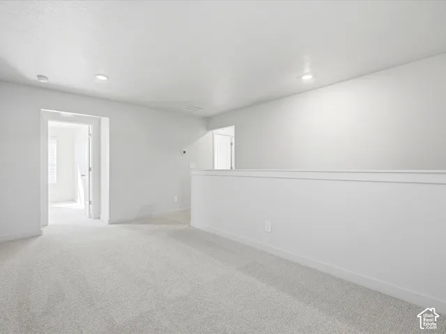 Neutral-toned wall-to-wall carpeting, recessed LED lighting, and a painted half-wall partition
