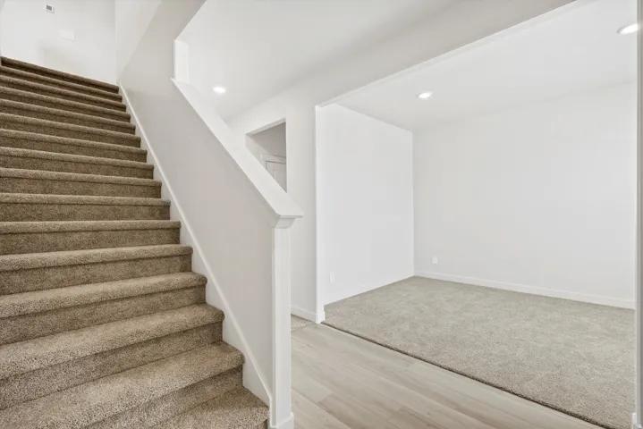 **DISCLAIMER** Interior package may vary. Carpeted staircase with white balustrade, recessed lighting, and wood-finish flooring