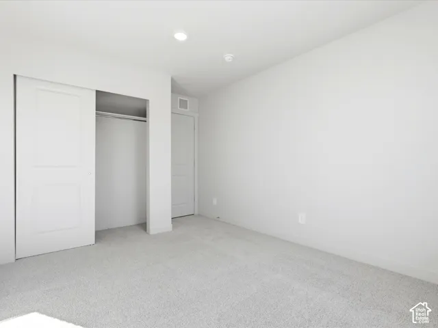 Neutral-toned interior featuring wall-to-wall carpeting, recessed ceiling lighting, and a closet with a two-panel sliding door