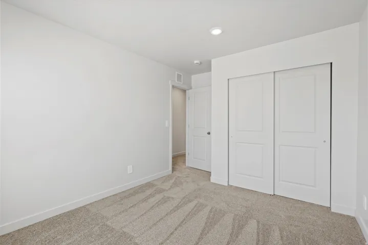 **DISCLAIMER** Interior package may vary. Carpeted room featuring a double sliding door closet with panel detailing, a recessed ceiling light, and a white baseboard trim