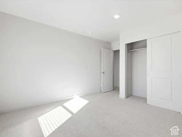 Neutral interior featuring wall-to-wall carpeting, recessed lighting, and a closet with sliding paneled doors