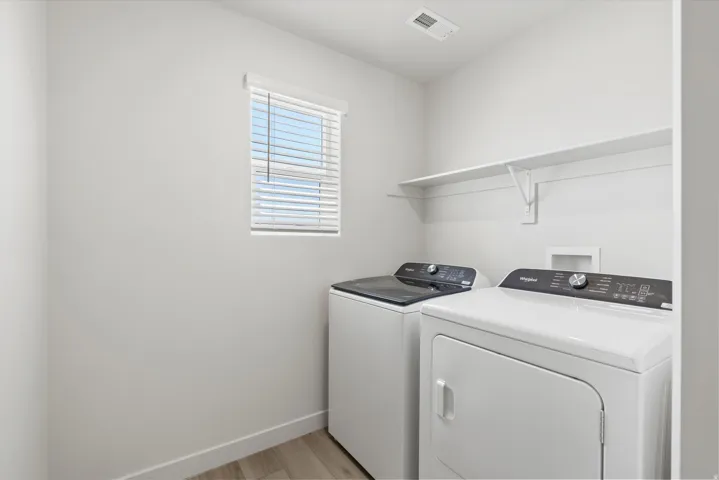 **DISCLAIMER** Interior package may vary. Dedicated laundry area featuring a window with blinds, light wood-finish flooring, and a built-in wall shelf
