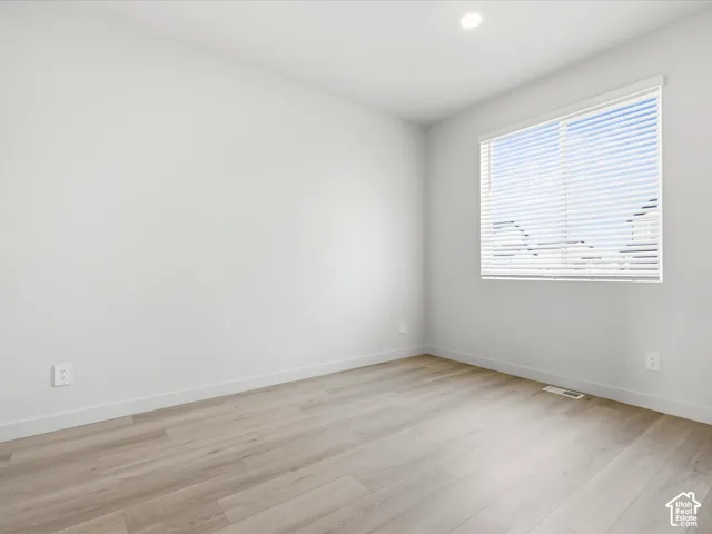 Neutral-toned walls, wood-finish flooring, recessed lighting, and a window with integrated blinds