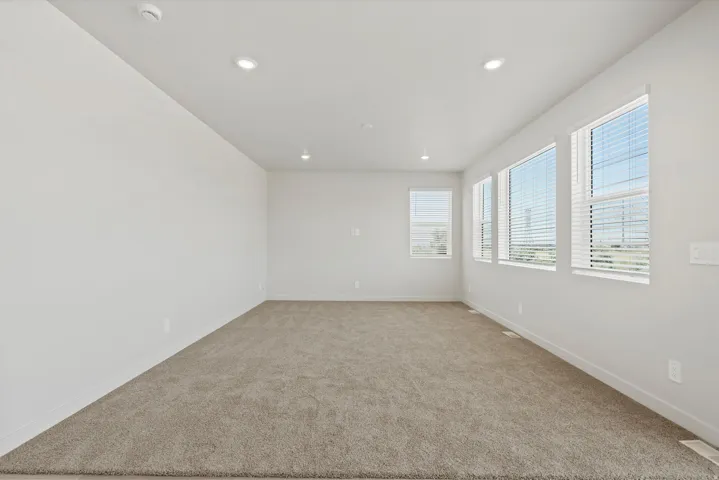 **DISCLAIMER** Interior package may vary. Bright interior space featuring a wall of multiple windows with blinds, recessed lighting, and neutral carpeting
