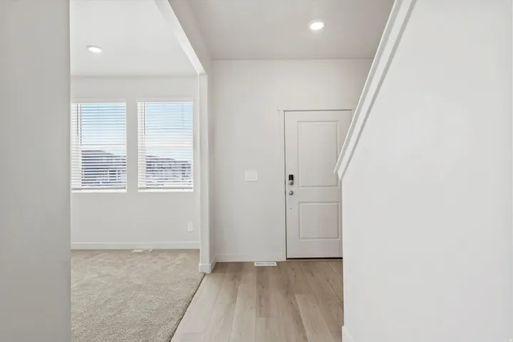 **DISCLAIMER** Interior package may vary. Entryway featuring light wood-finish flooring, a white paneled door with smart lock hardware, and recessed lighting