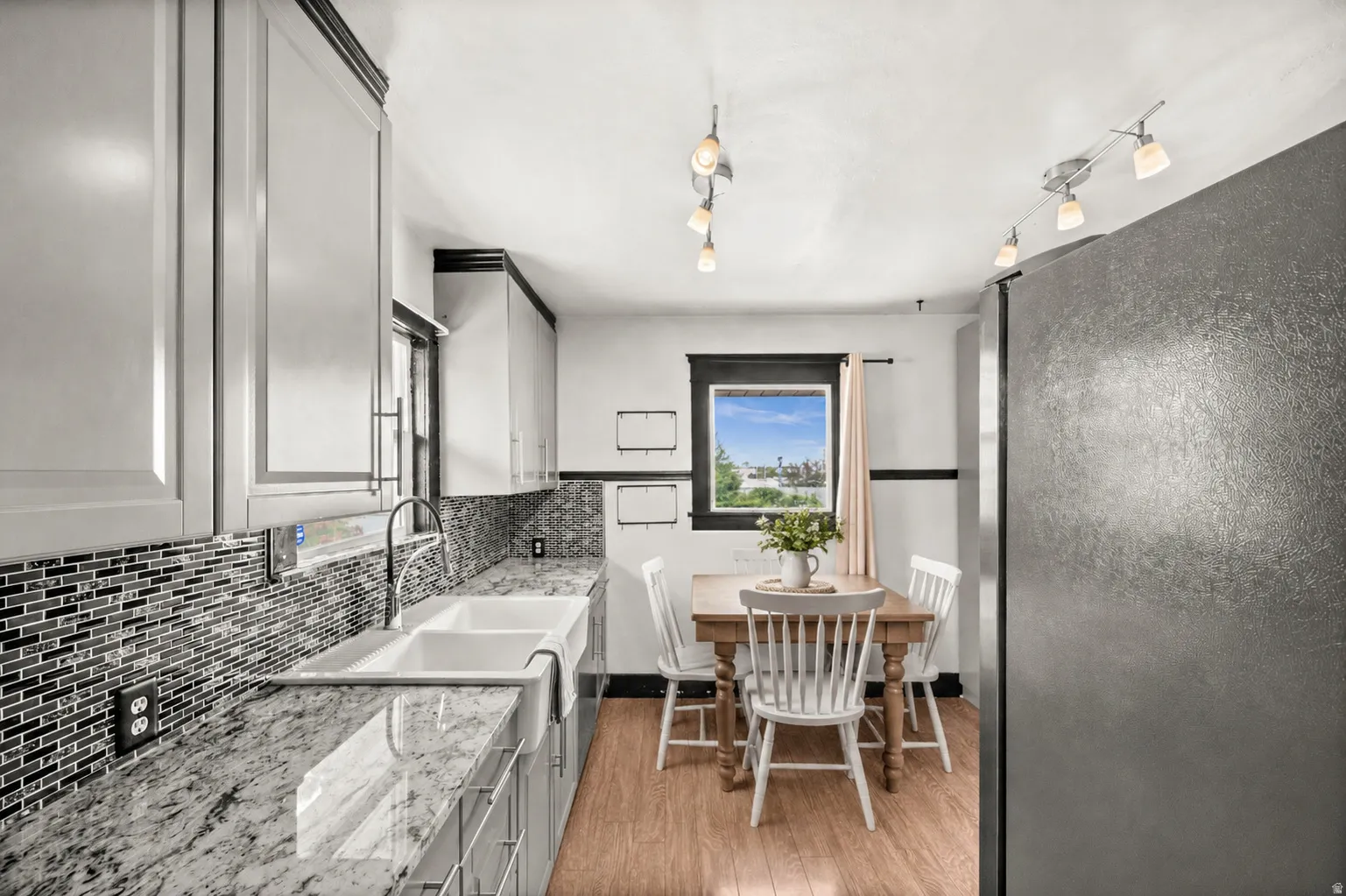 Modern kitchen featuring light cabinetry, a textured tile backsplash, and a double basin farmhouse sink with a gooseneck faucet