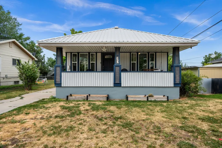 Single-story residence featuring a covered front porch with decorative columns, a metal roof, and horizontal siding