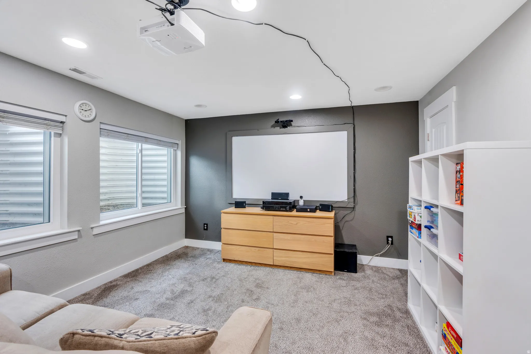 Recreation room featuring recessed lighting, a ceiling-mounted projector, and two egress windows