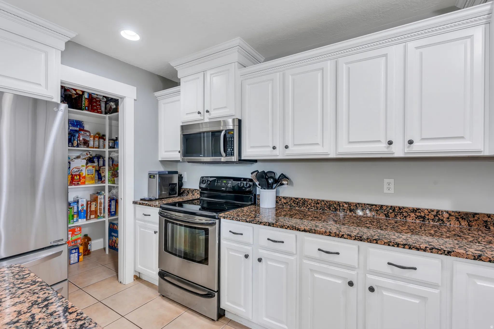 Kitchen featuring white cabinetry with dark hardware, stainless steel appliances, and granite-style countertops