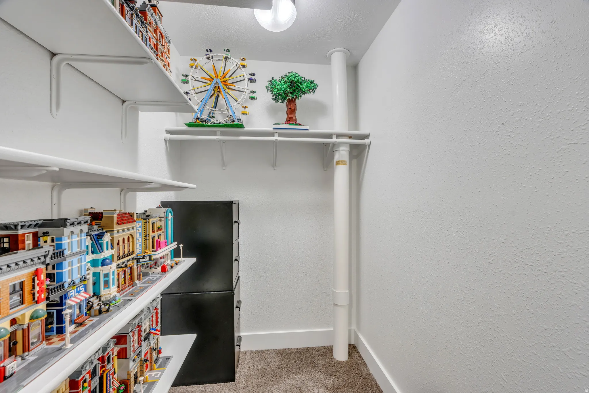 Integrated shelving system with multiple white shelves, textured white walls, and a ceiling-mounted light fixture