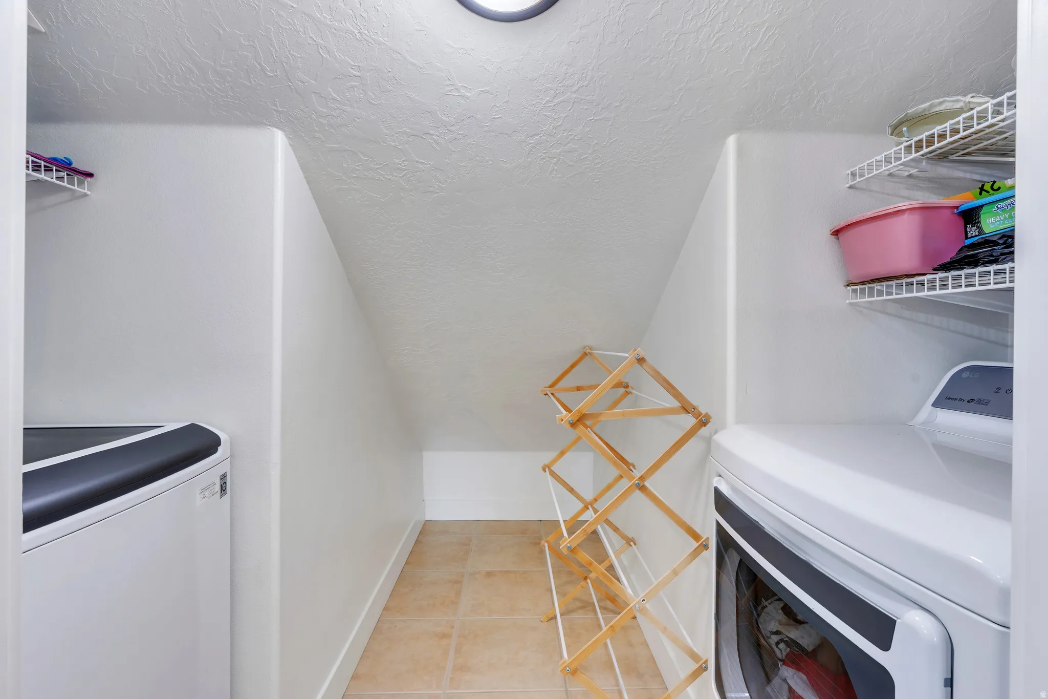 Laundry area featuring tile flooring, white walls, and an overhead light fixture