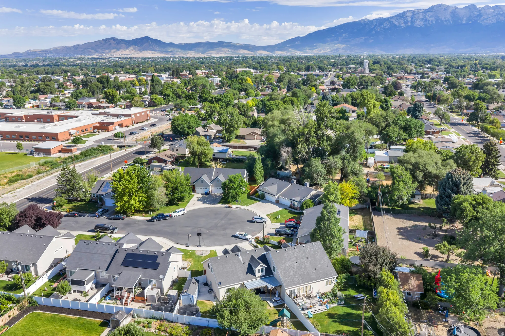 Cul-de-sac properties featuring mature trees, mountain backdrop, and varying rooflines