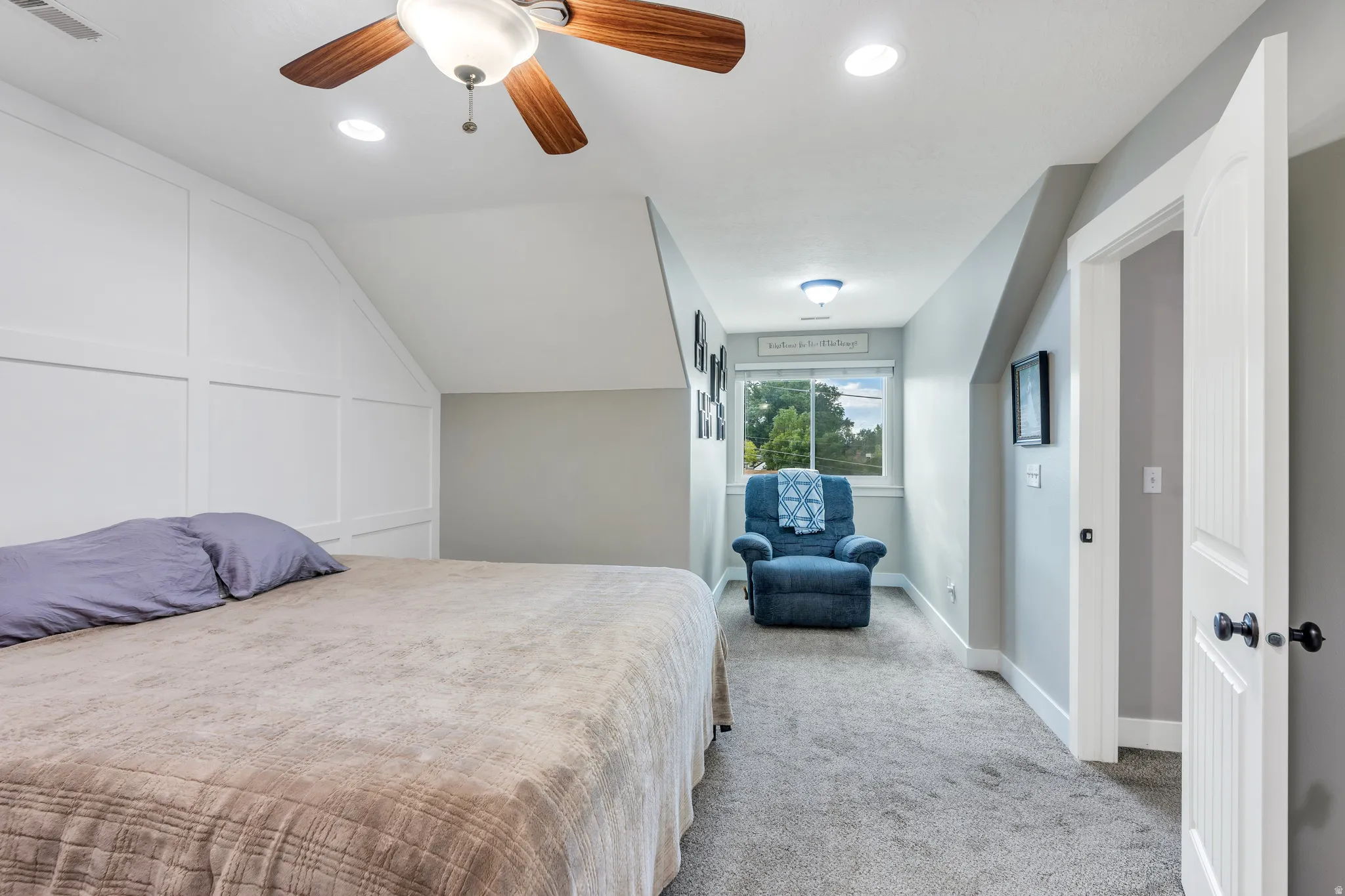 Bedroom featuring a ceiling fan with light fixture, recessed lighting, carpet flooring, a window, and a paneled accent wall