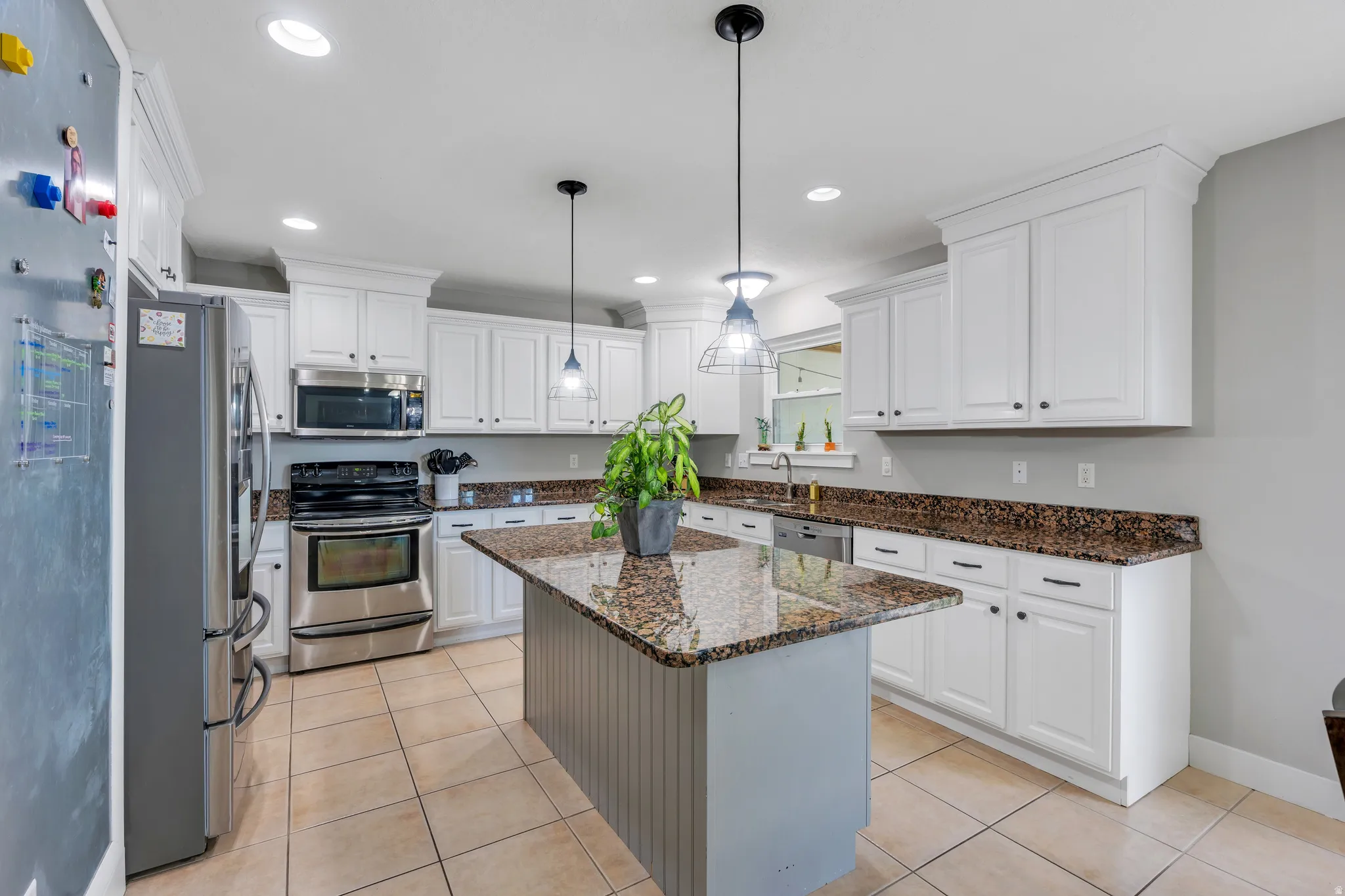 Kitchen featuring a central island with a granite countertop, white cabinetry with dark hardware, recessed lighting, and tile flooring