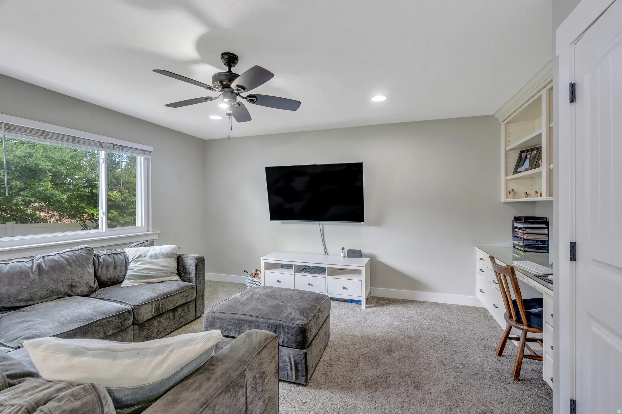 Carpeted interior space featuring a large window, recessed lighting, and a ceiling fan with integrated lighting