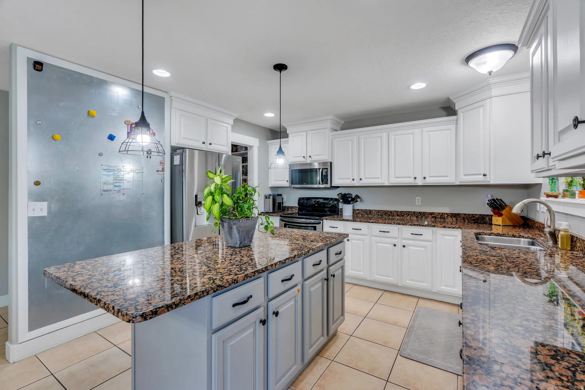 Kitchen featuring a central island with a granite countertop, white cabinetry with dark hardware, recessed lighting, and tile flooring